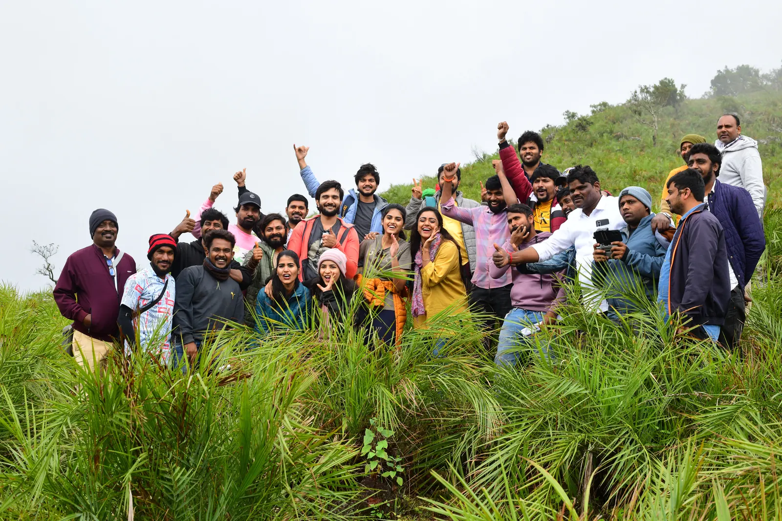 The cast and crew of Dharmasthala Niyojakavargam celebrating on a hillside location